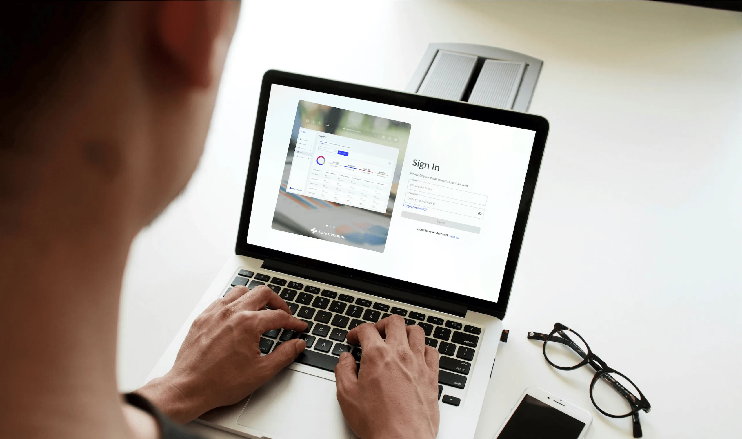A person signing in to the Blue Cimarron billing platform on a laptop, next to a preview of its reports dashboard.