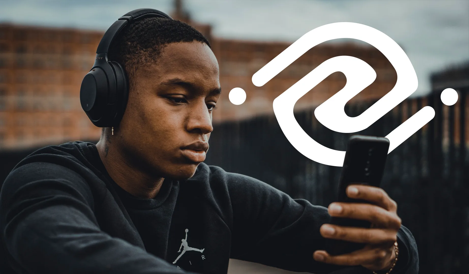 Earbuds logo over a photo of a young man listening to music on headphones while looking at his phone outdoors