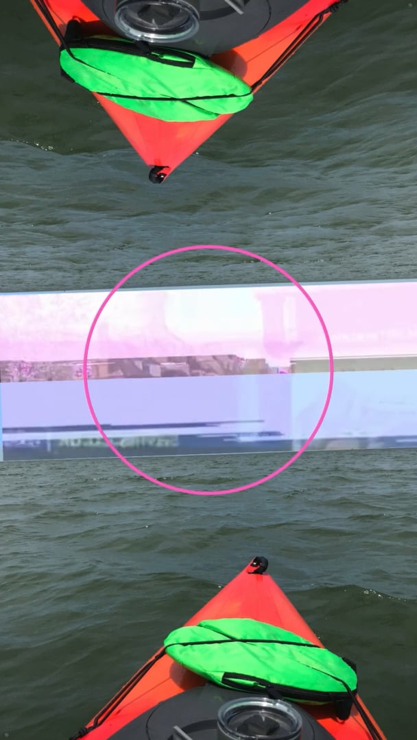 Bright orange kayak with neon green bag floating on water, mirrored with a pink-circled glitch strip across the middle.