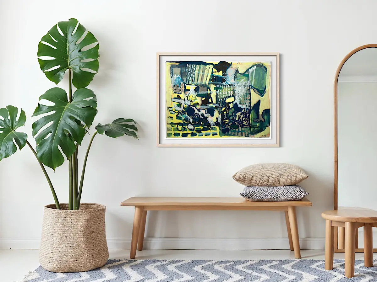 Framed abstract painting in shades of blue, green, and yellow hangs above a light wood bench with neutral pillows. A large monstera plant in a woven basket and a floor mirror complete the airy, modern setting.