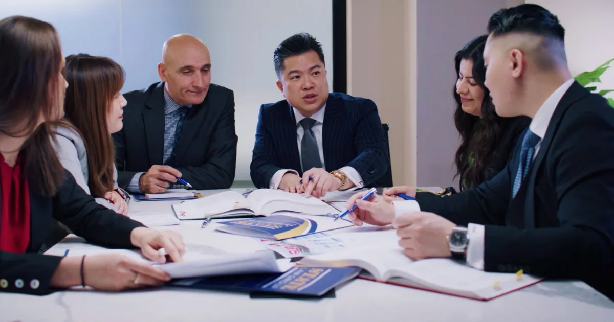 Team photo of lawyers sitting around a table planning for a client's case