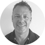 Black-and-white headshot of a smiling middle-aged man with short hair.