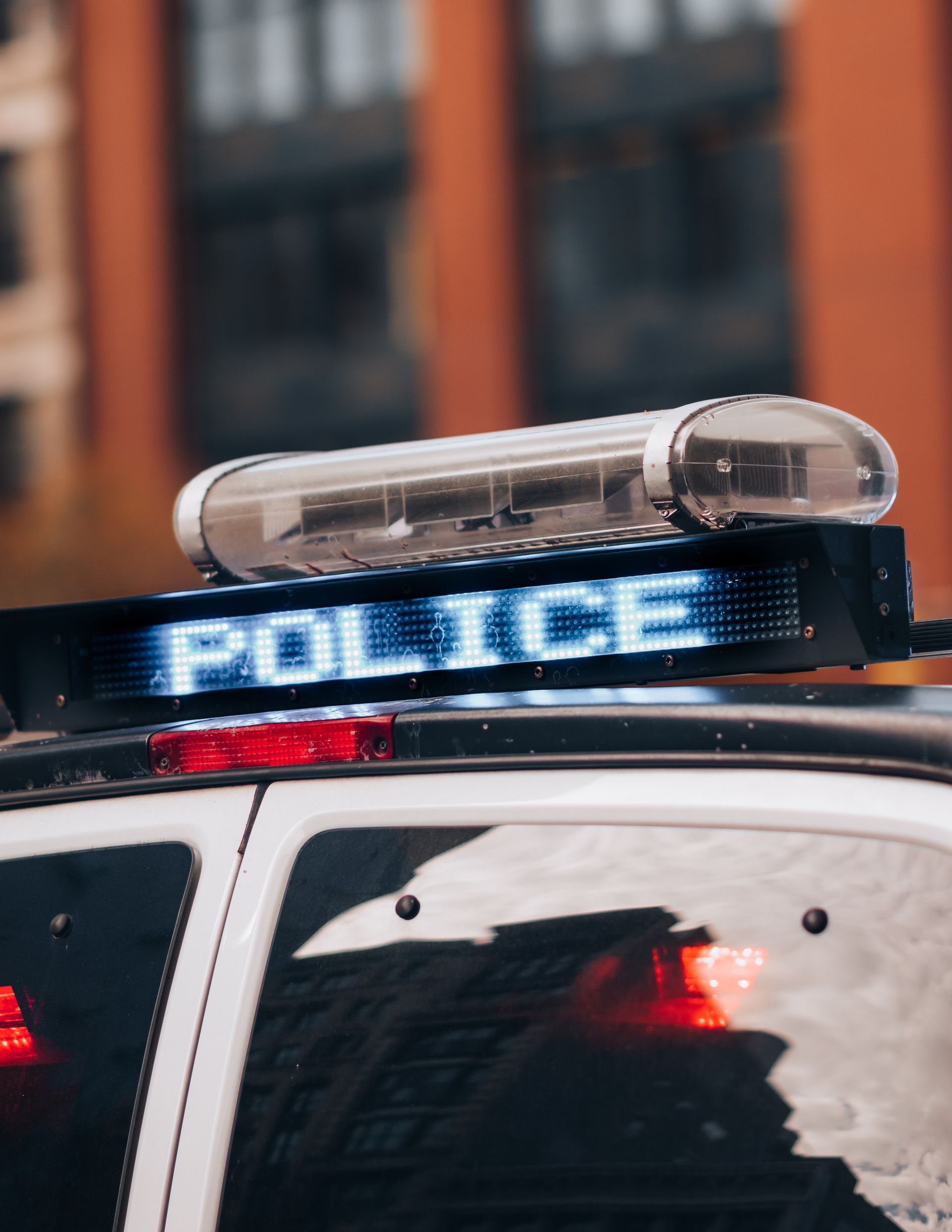 Detailed view of a police car with flashing lights in an urban environment, emphasizing safety. Photo by Gabriel Hohol via Pexels.com