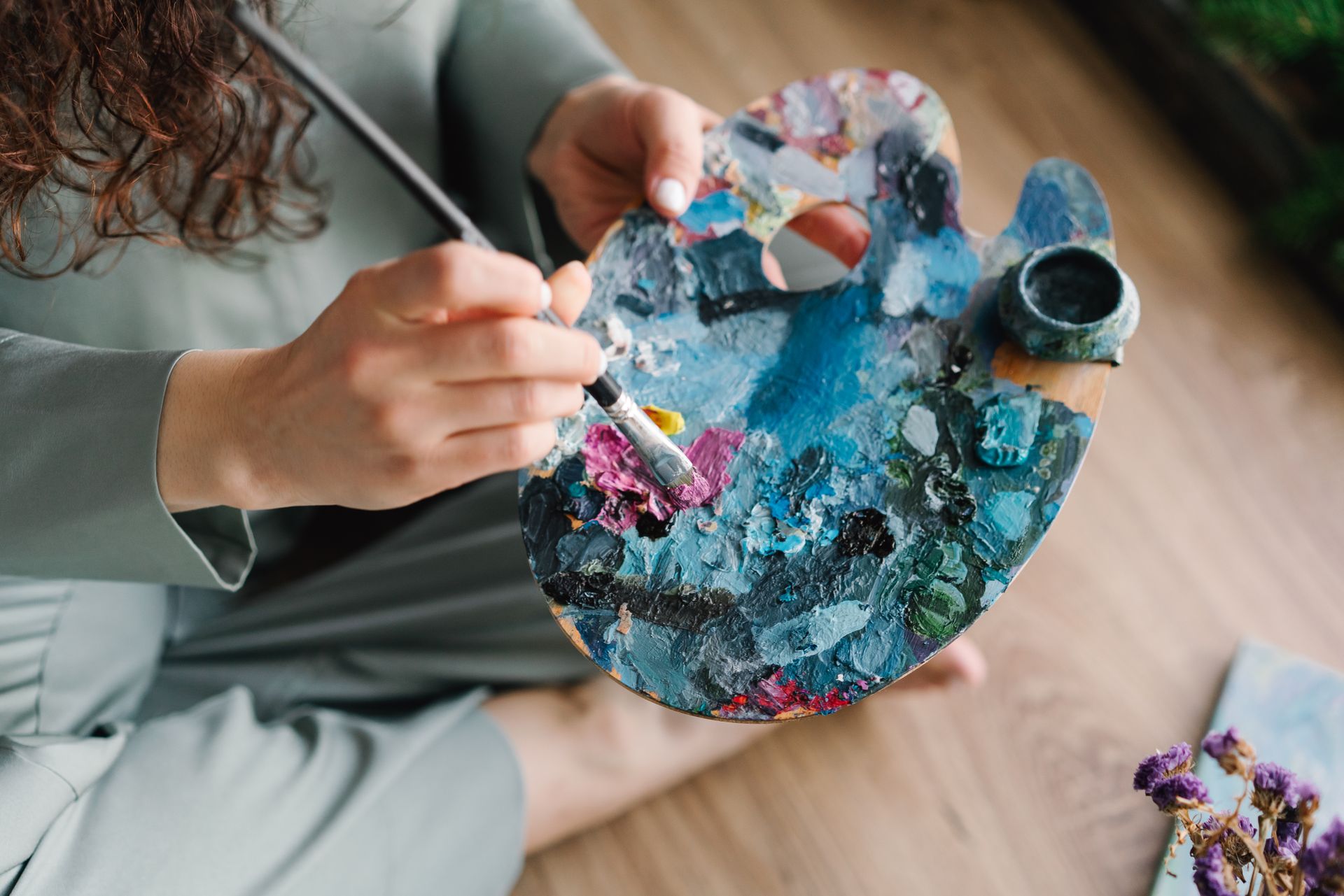 Close-up of hands painting on a colorful palette, showcasing creativity and artistry. Photo by Mikhail Nilov, via Pexels.com