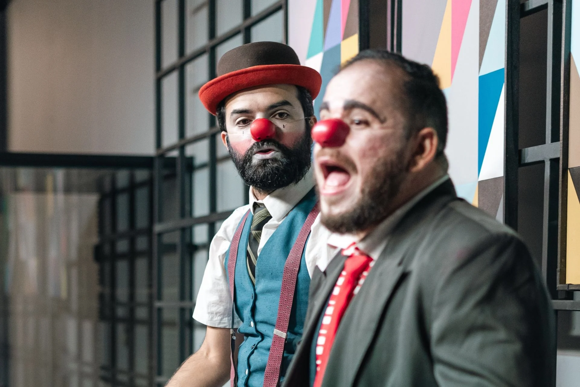Two male clowns with red noses perform expressively on stage, adding humor and charm. Photo by SAULO LEITE via Pexels.com