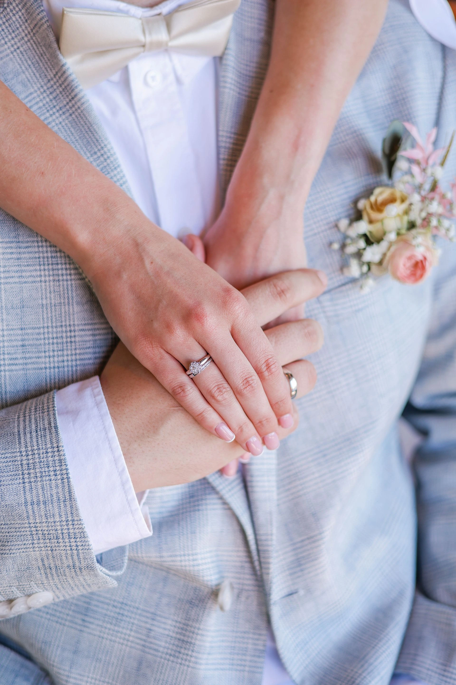 A close-up of newlyweds' hands showcasing wedding rings and floral details. Photo by Valeria Boltneva via Pexels.com