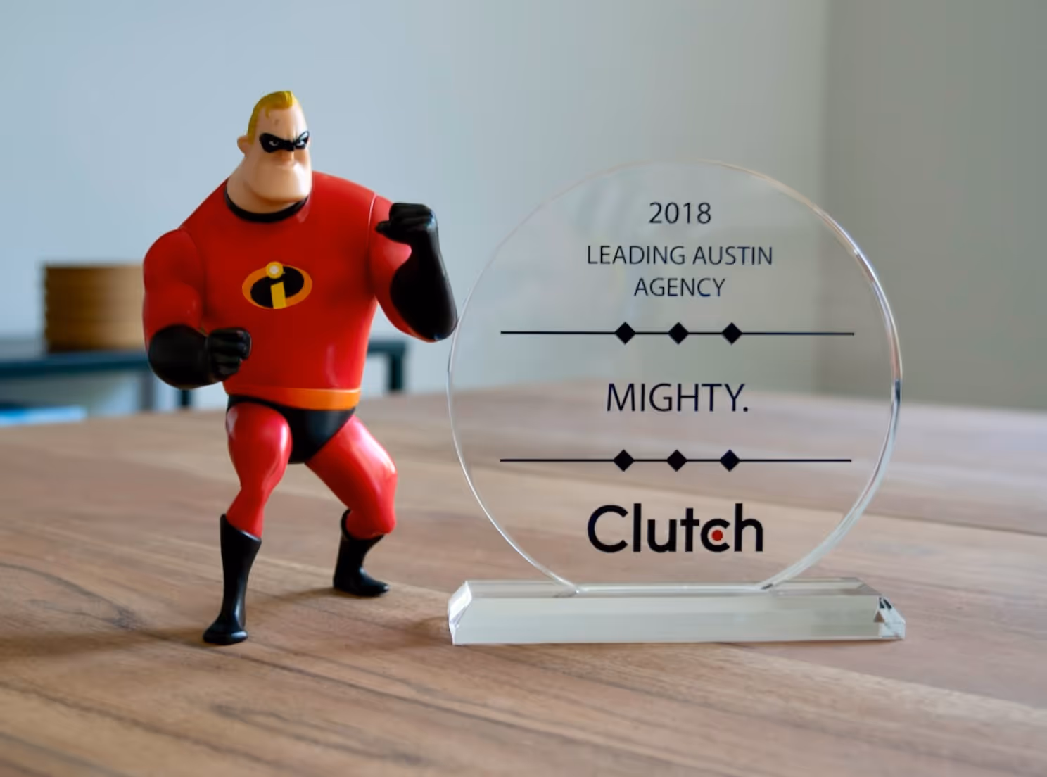 Mr. Incredible figure posed next to a 2018 Clutch award for Leading Austin Agency named Mighty.