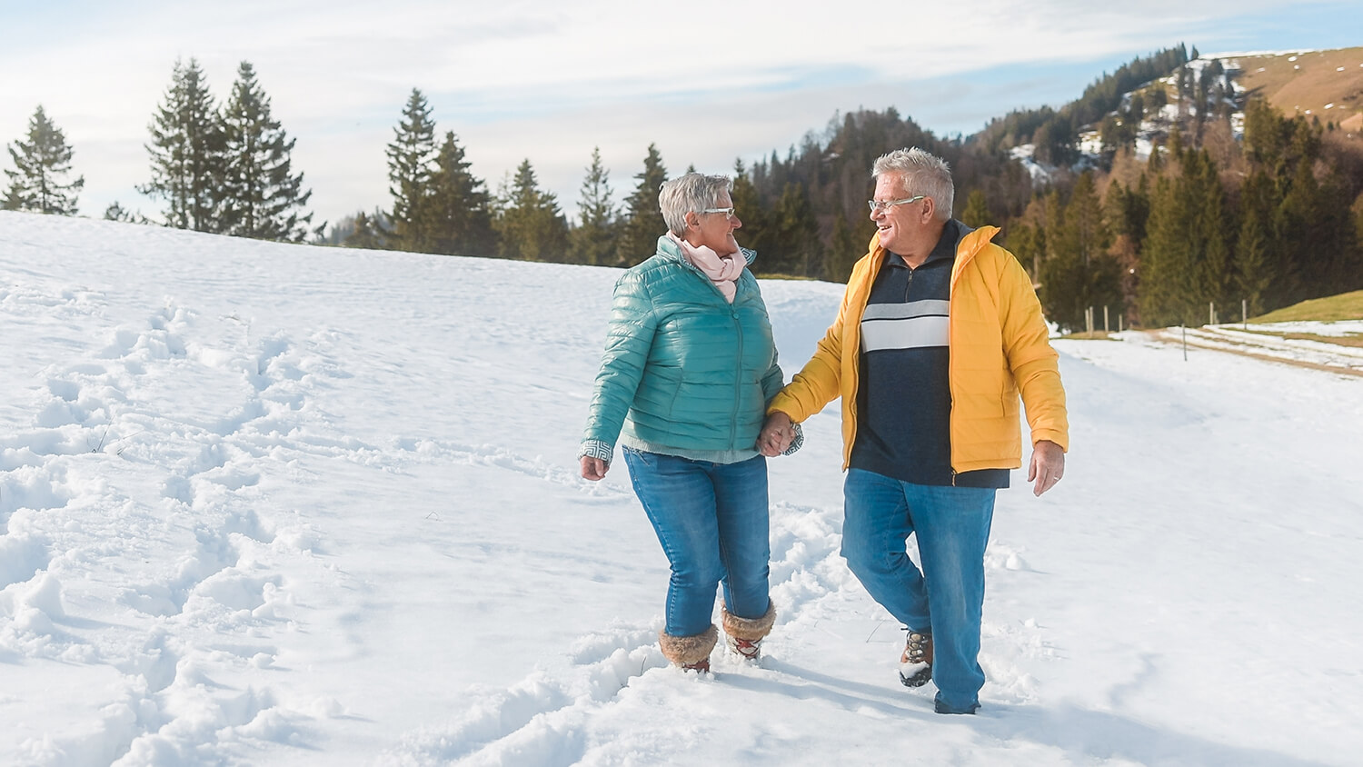 Happy Senior Couple Walking Together Through The Snow During Winter Time - Joyful Elderly People