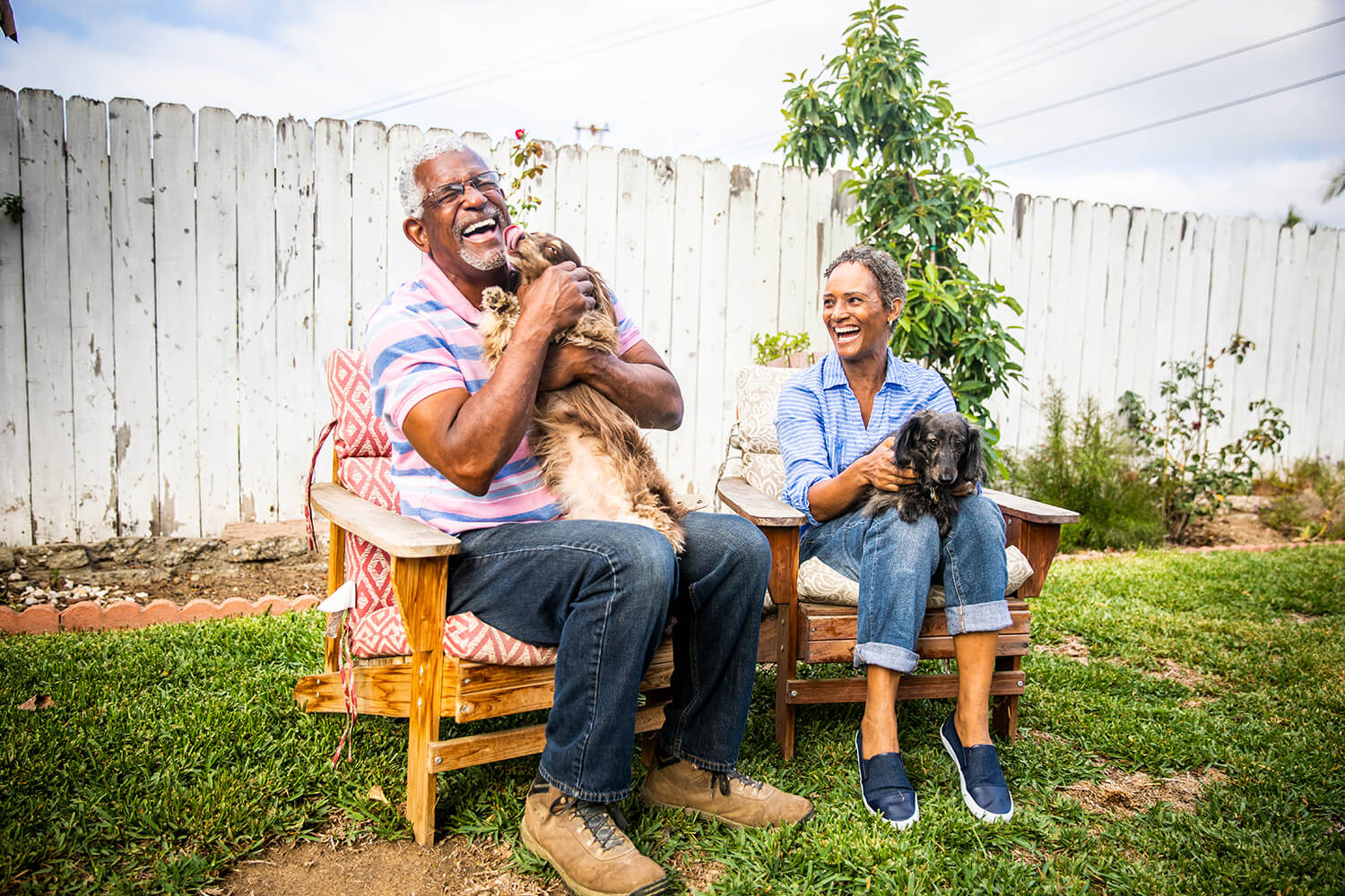 A senior black couple playing outdoors with their two dachshunds