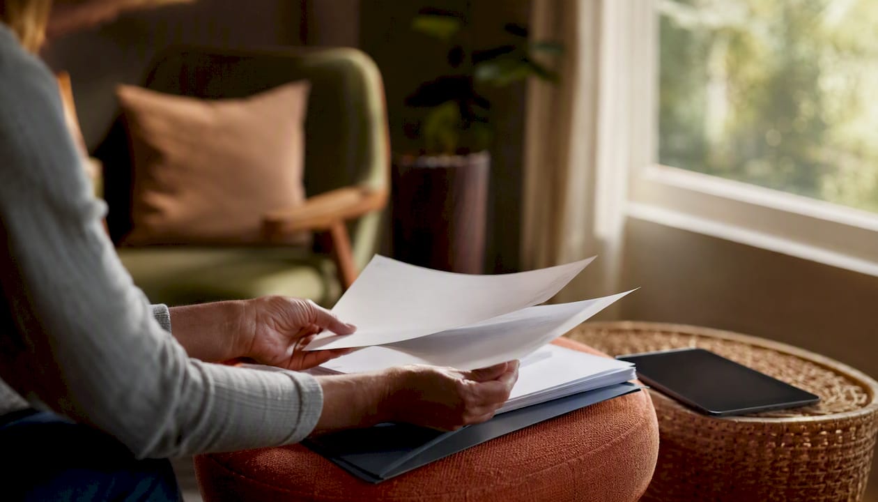 Hands organizing pension documents near tablet