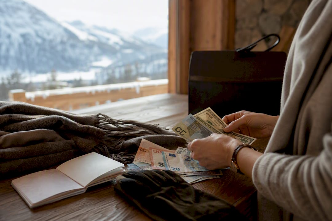 Hands with multiple currencies at alpine home entry
