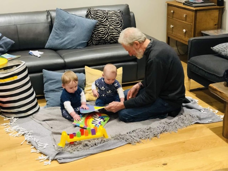Granddad sits and plays with twin toddlers at child-friendly self catering holiday cottage Gwelmor in Widemouth Bay, north Cornwall