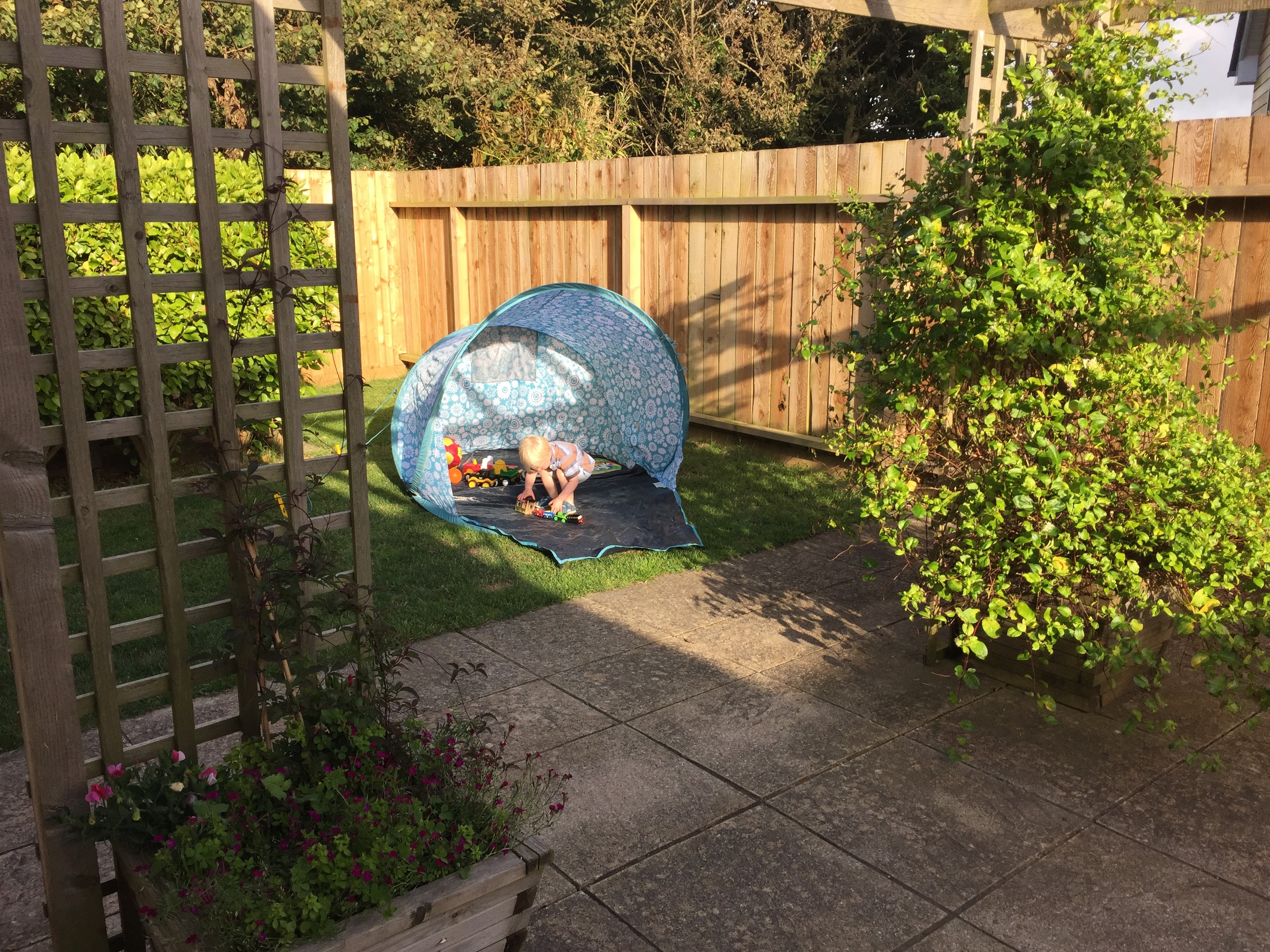 Young boy plays by himself in the fully enclosed garden at Gwelmor, in Widemouth Bay