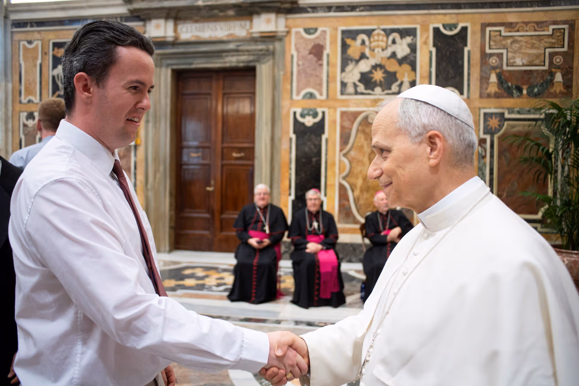 Patrick is pictured in a marble-walled hall in the Vatican, shaking hands with Pope Leo