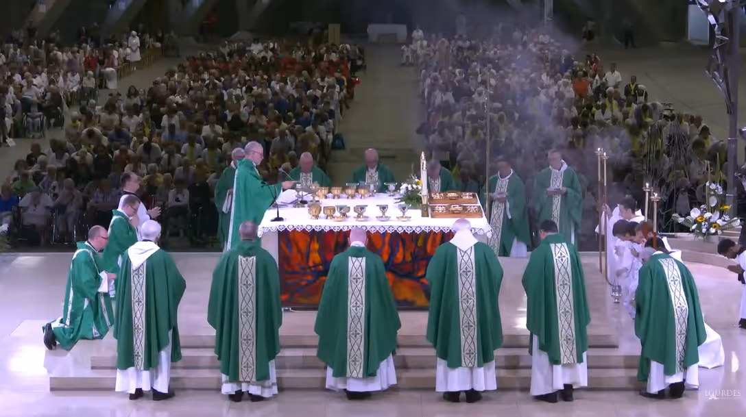 Thousands of lay faithful can be seen behind the huge altar in the Underground Basilica, around which ten bishops are gathered.
