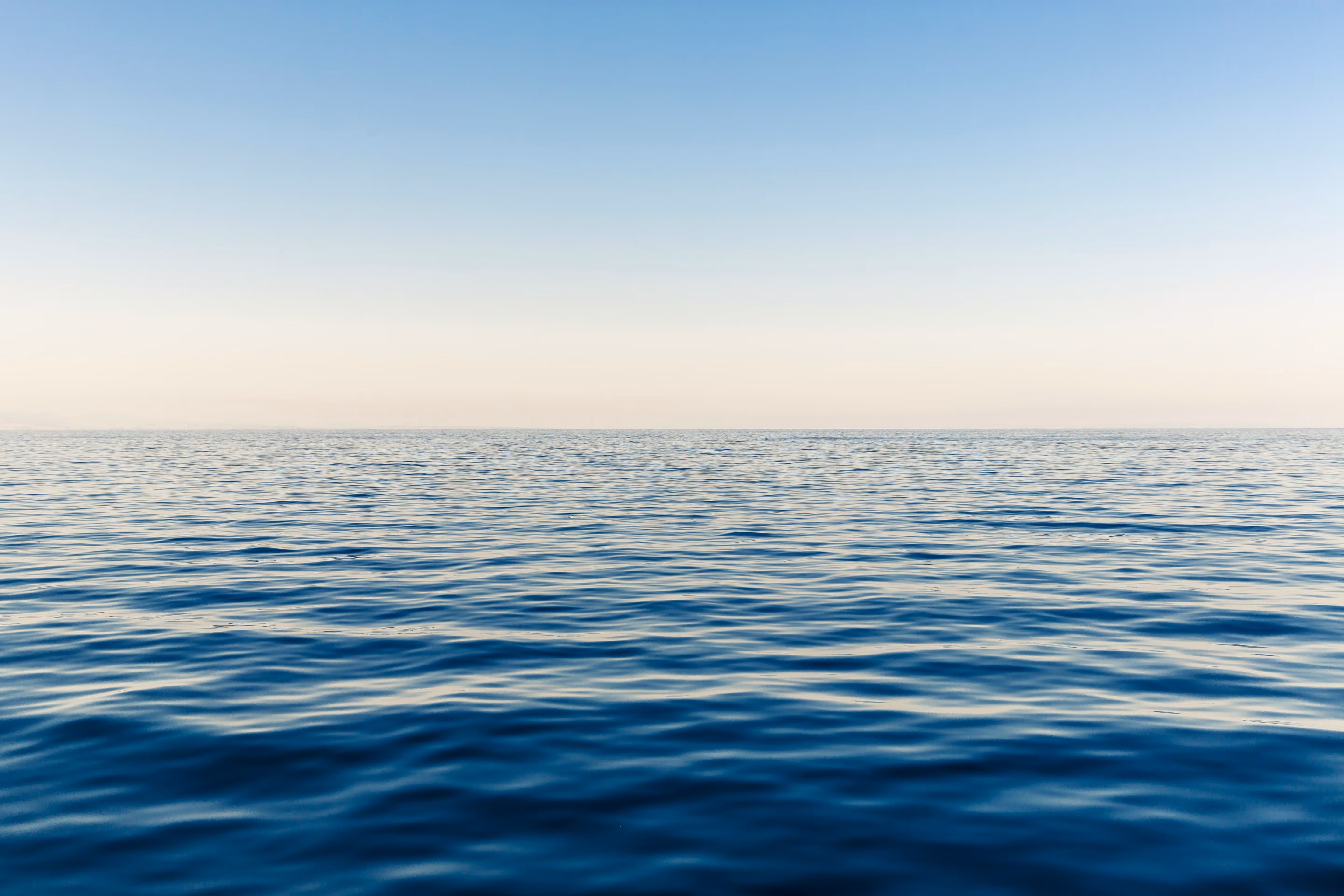 Photo shows a calm sea, looking towards a pale horizon