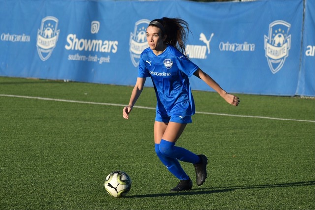 Charlotte Soccer Academy female soccer player dribbling the ball wearing a blue uniform