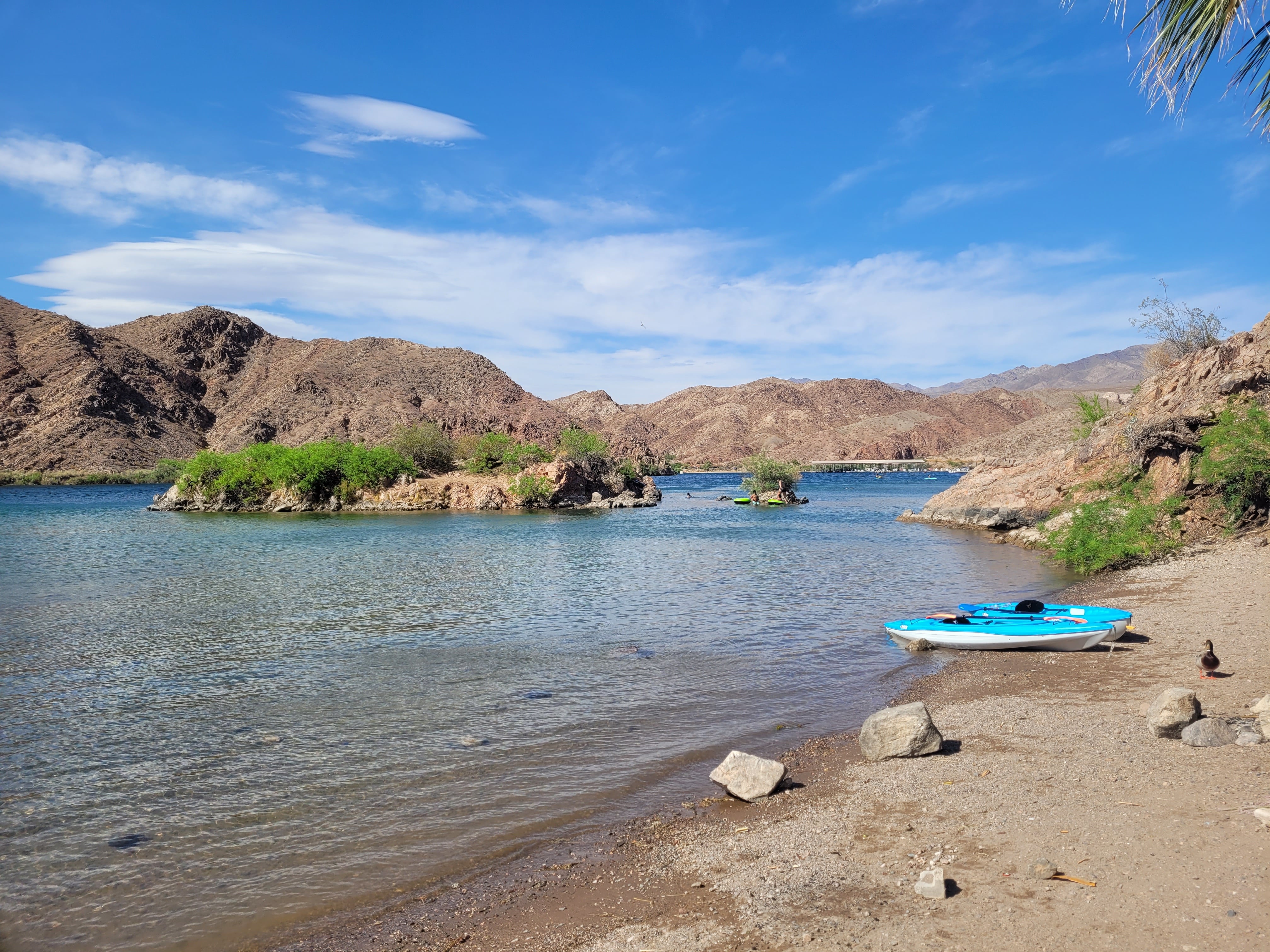 Views of the beautiful blue and green Colorado River with the Black Canyons around the water. There are two kayaks along the shore of Willow Beach.
