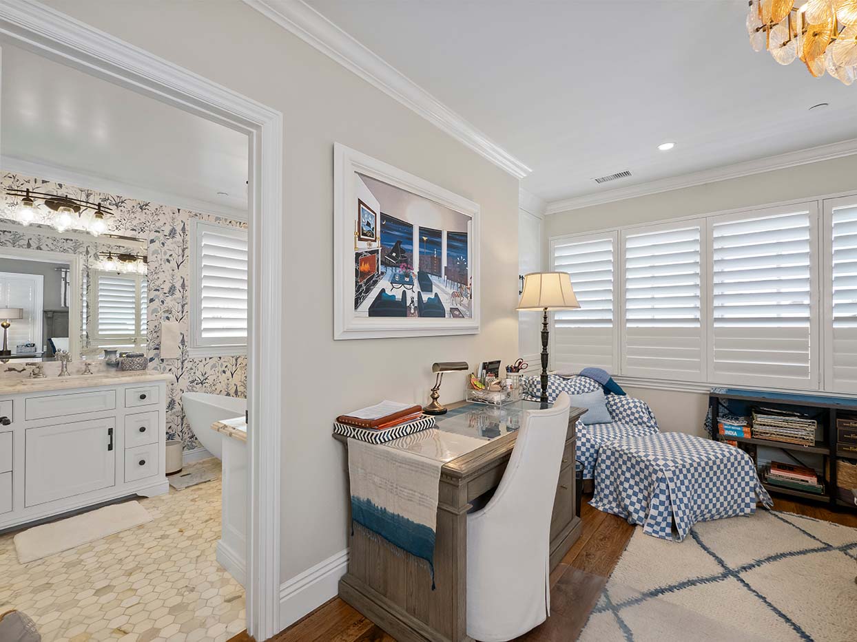Bedroom sitting area at 220 Collins with a writing desk, a blue check-pattern bench, and a view into the ensuite bathroom
