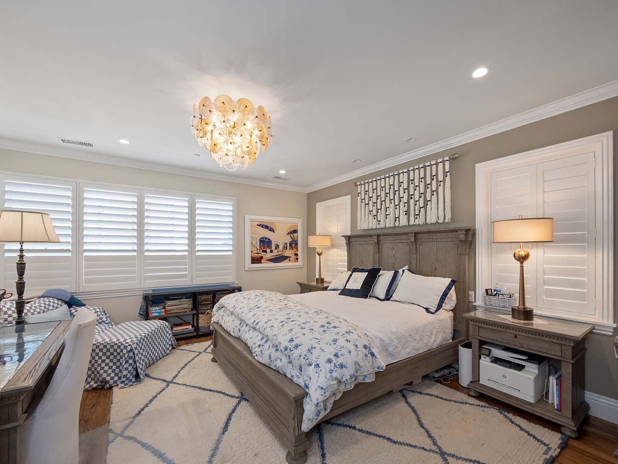 Primary bedroom at 220 Collins with a carved wood headboard, blue and white bedding, and a glass bubble chandelier