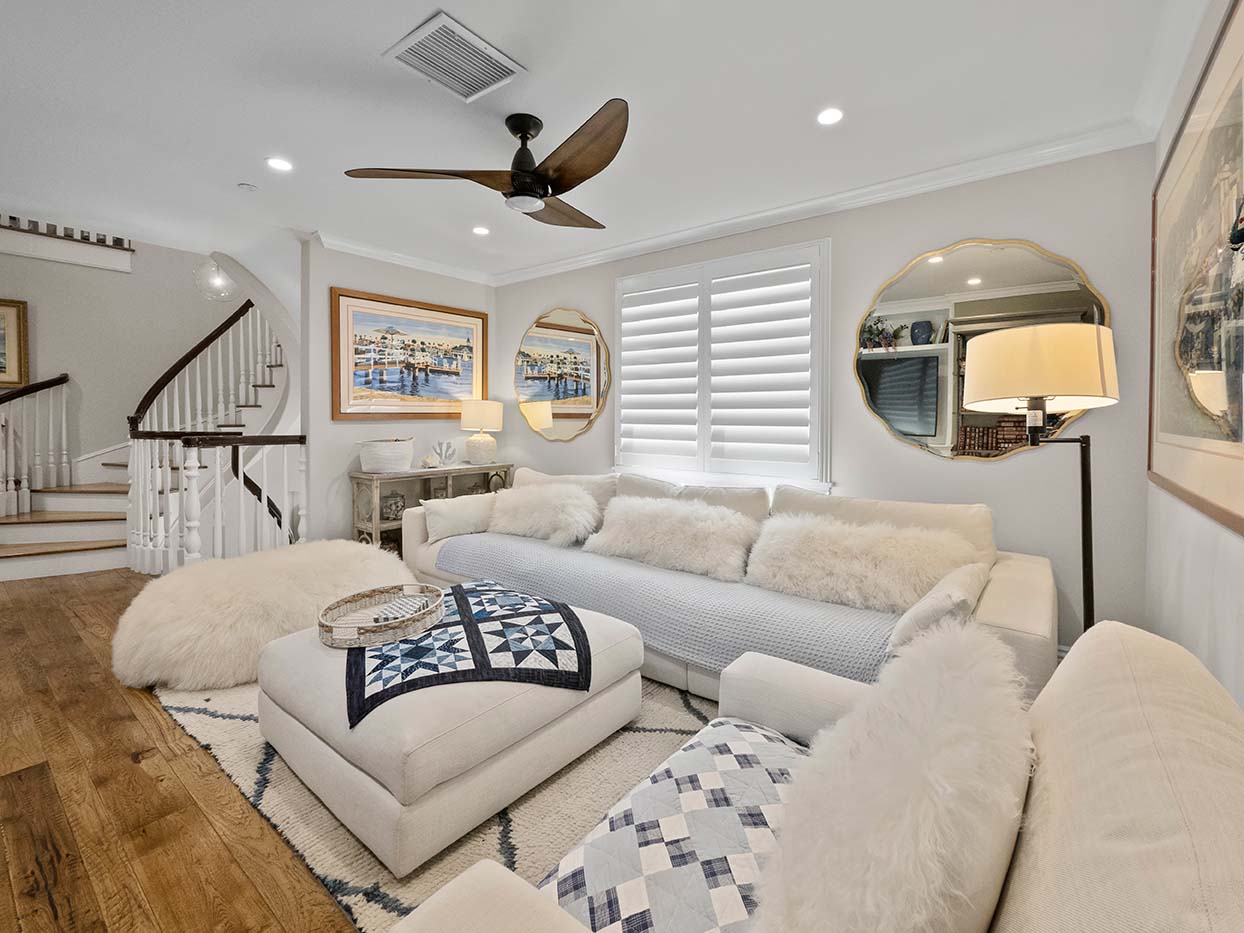 Upstairs living room at 220 Collins with a white sectional sofa, sheepskin pillows, and coastal artwork