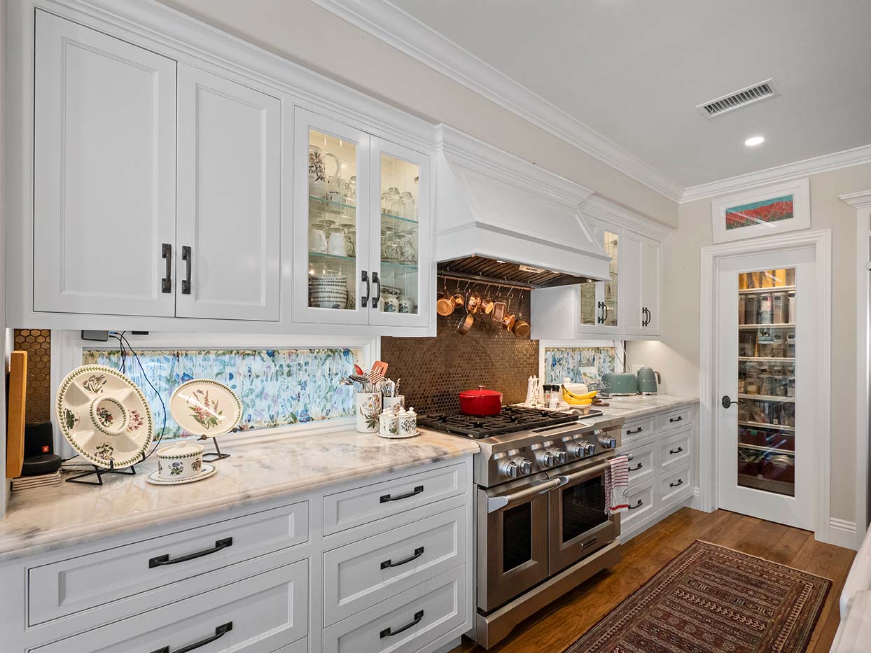 Kitchen at 220 Collins with white cabinetry, a glass-front pantry door, and a stainless steel range
