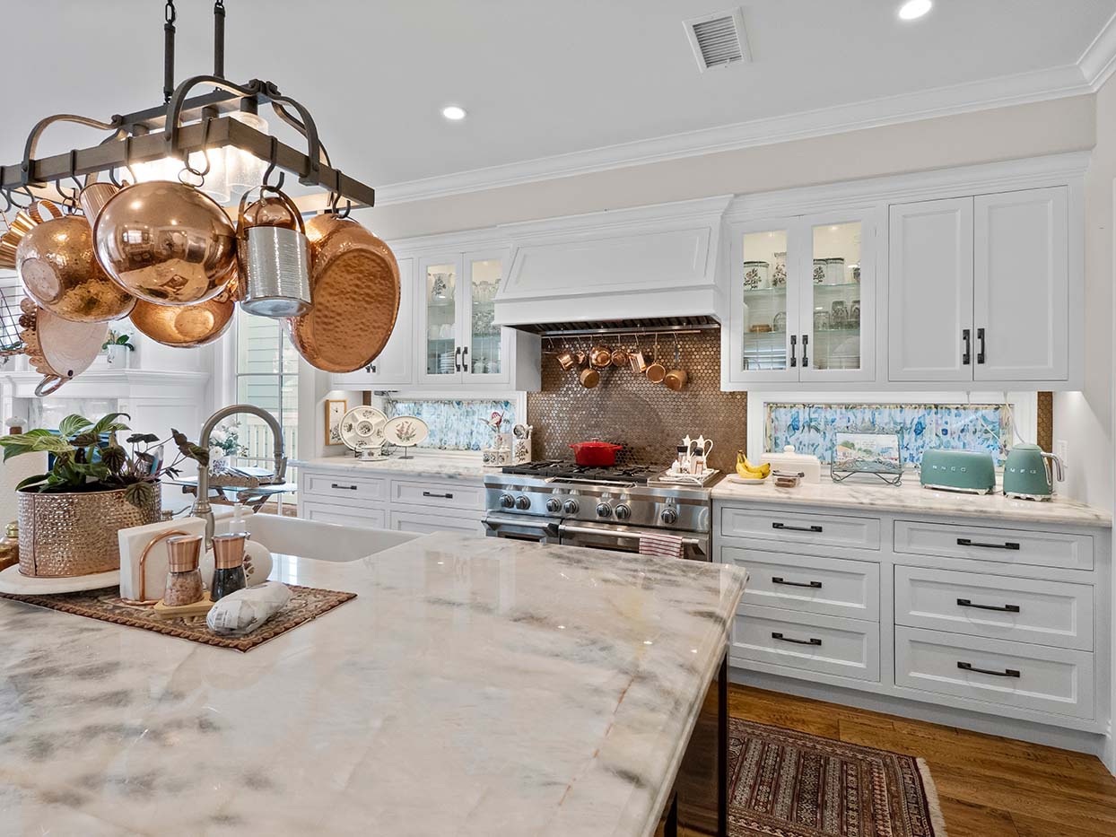 Kitchen at 220 Collins with a hammered copper pot rack, marble countertops, and a stainless steel range