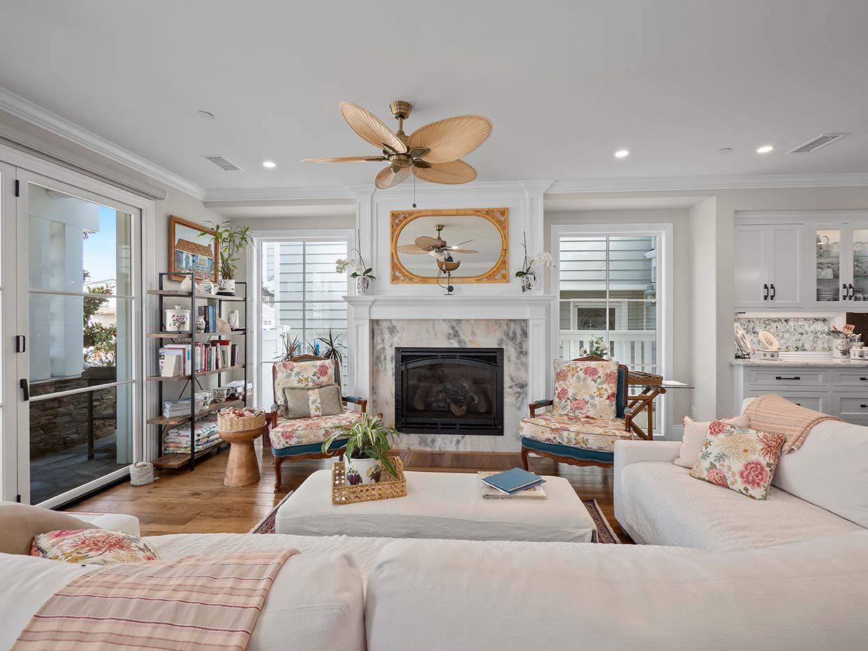 Living room seating area at 220 Collins with floral armchairs, a marble fireplace, and a view into the kitchen