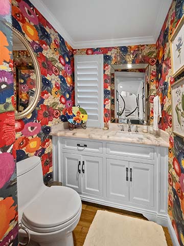 Powder room at 220 Collins with bold red floral wallpaper and a white marble-top vanity