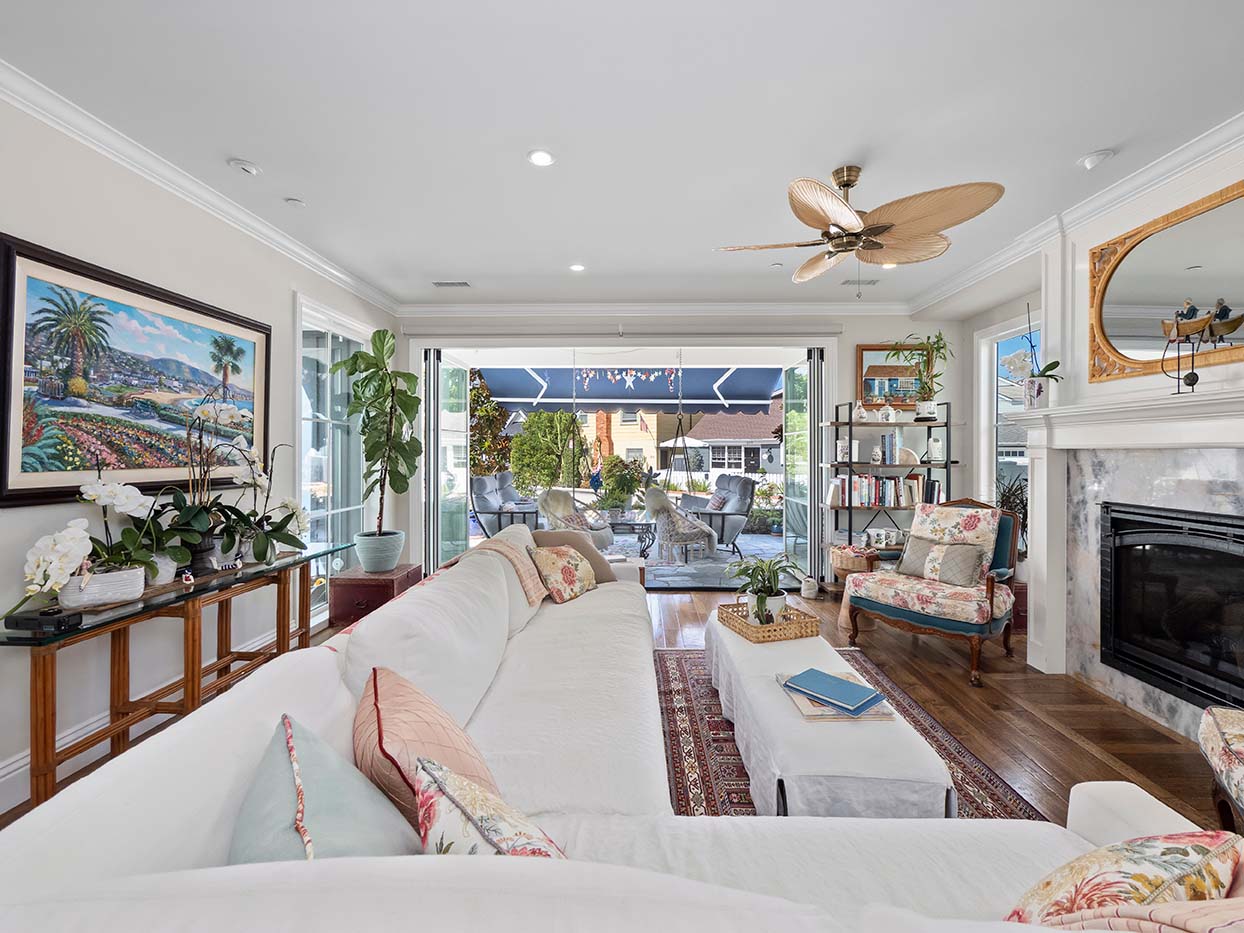 Living room at 220 Collins with folding glass doors open to the patio, coastal artwork, and an antique area rug