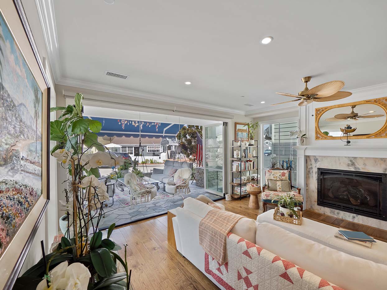 Living room at 220 Collins with a white sofa, marble fireplace, and folding glass doors opening to the back patio