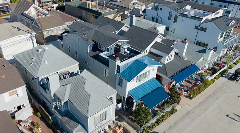 Aerial view of the 220 Collins beach house exterior with a rooftop deck and blue standing-seam roof accents among neighboring homes
