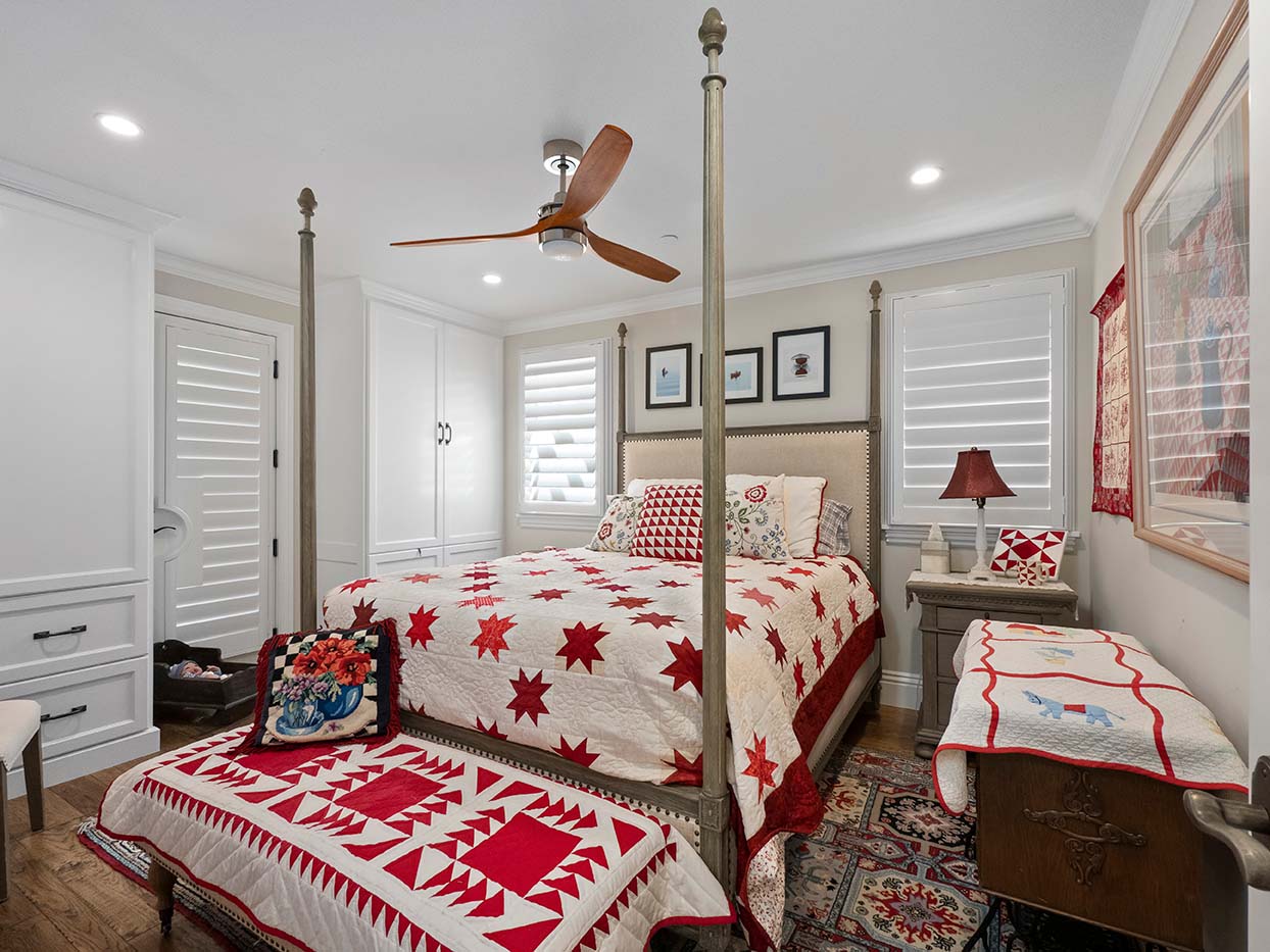 Bedroom at 220 Collins with a four-poster bed, a red and white star quilt, and coordinating red accents