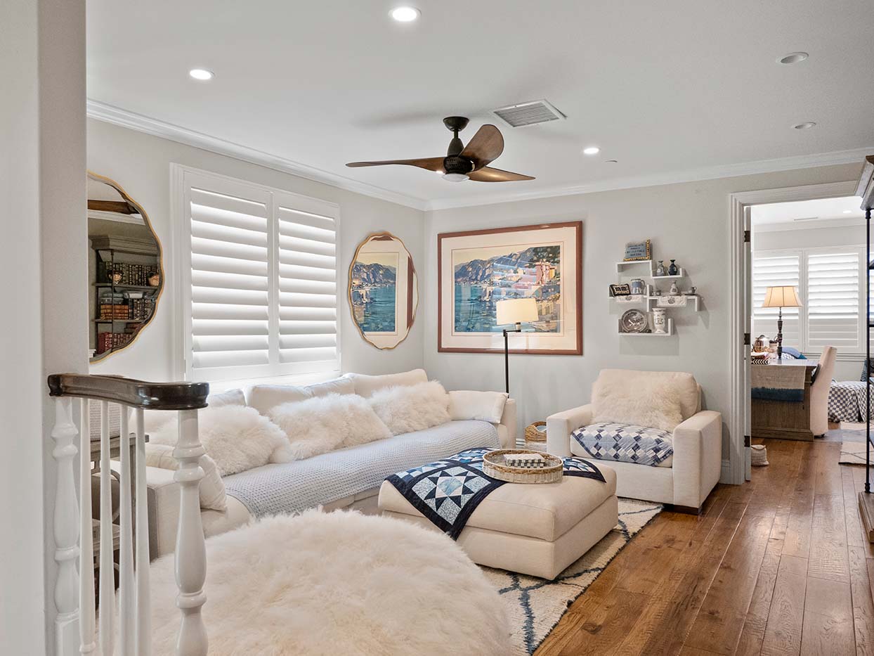 Loft living area at 220 Collins with a white sectional sofa, sheepskin pillows, and framed coastal artwork