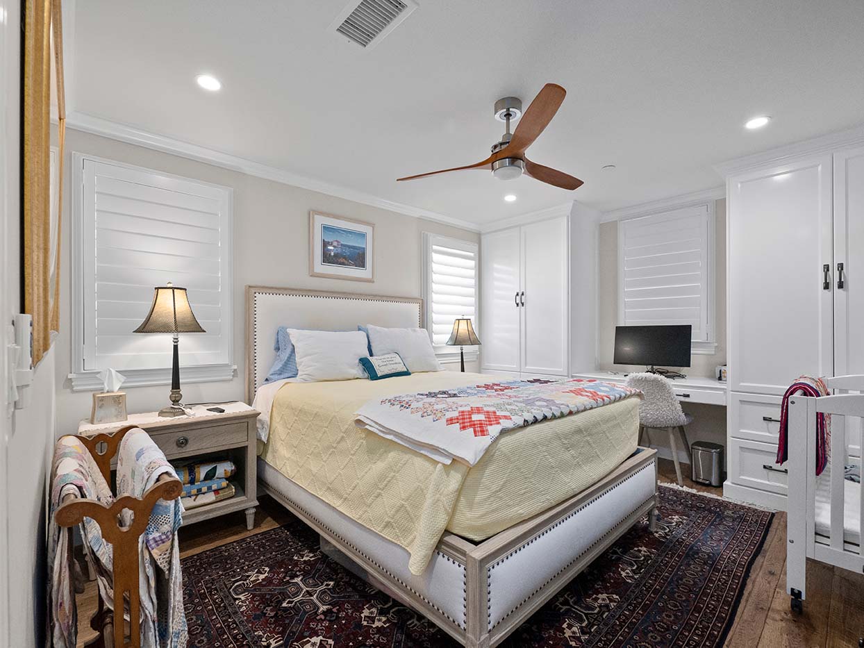 Bedroom at 220 Collins with an upholstered bed, a patchwork quilt, a built-in desk, and a crib in the corner