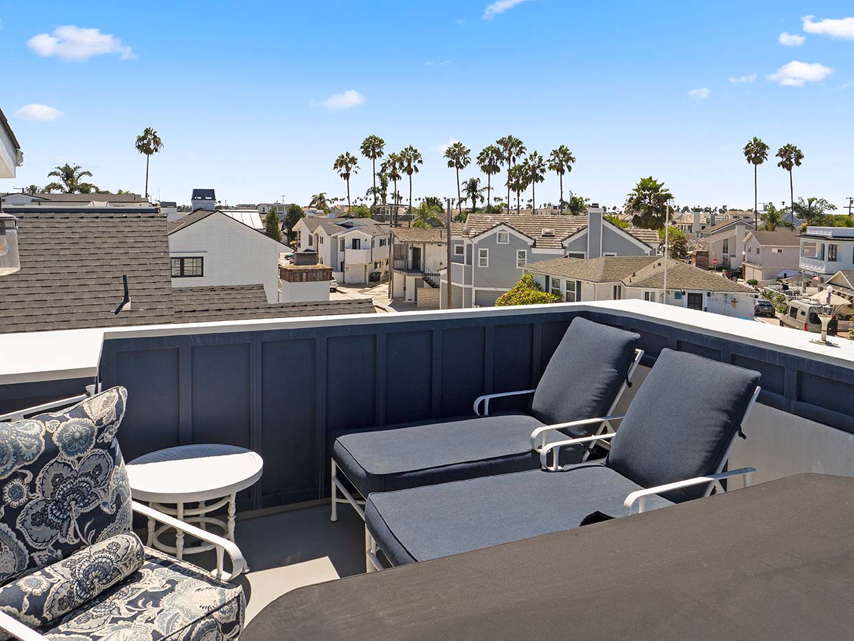 Rooftop deck at 220 Collins with chaise lounges and panoramic views of palm trees and neighboring rooftops