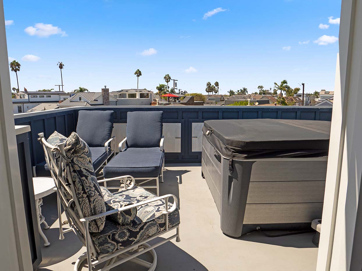 Rooftop deck at 220 Collins with lounge chairs and a hot tub overlooking the neighborhood and palm trees