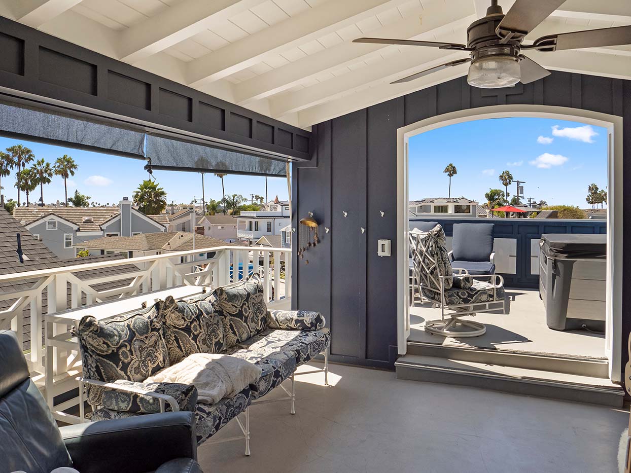 Covered rooftop deck seating area at 220 Collins opening to a sundeck with a hot tub and palm tree views