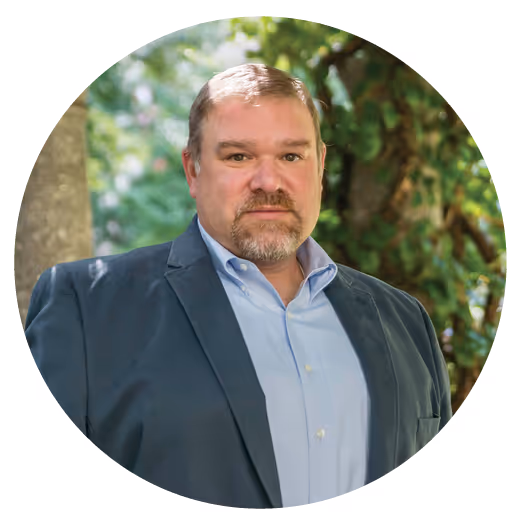 Chris Dynia, a white man wearing a light blue dress shirt and a navy blue suit jacket. 