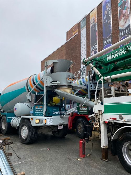 The front of a mixer truck, in the process of pouring concrete.