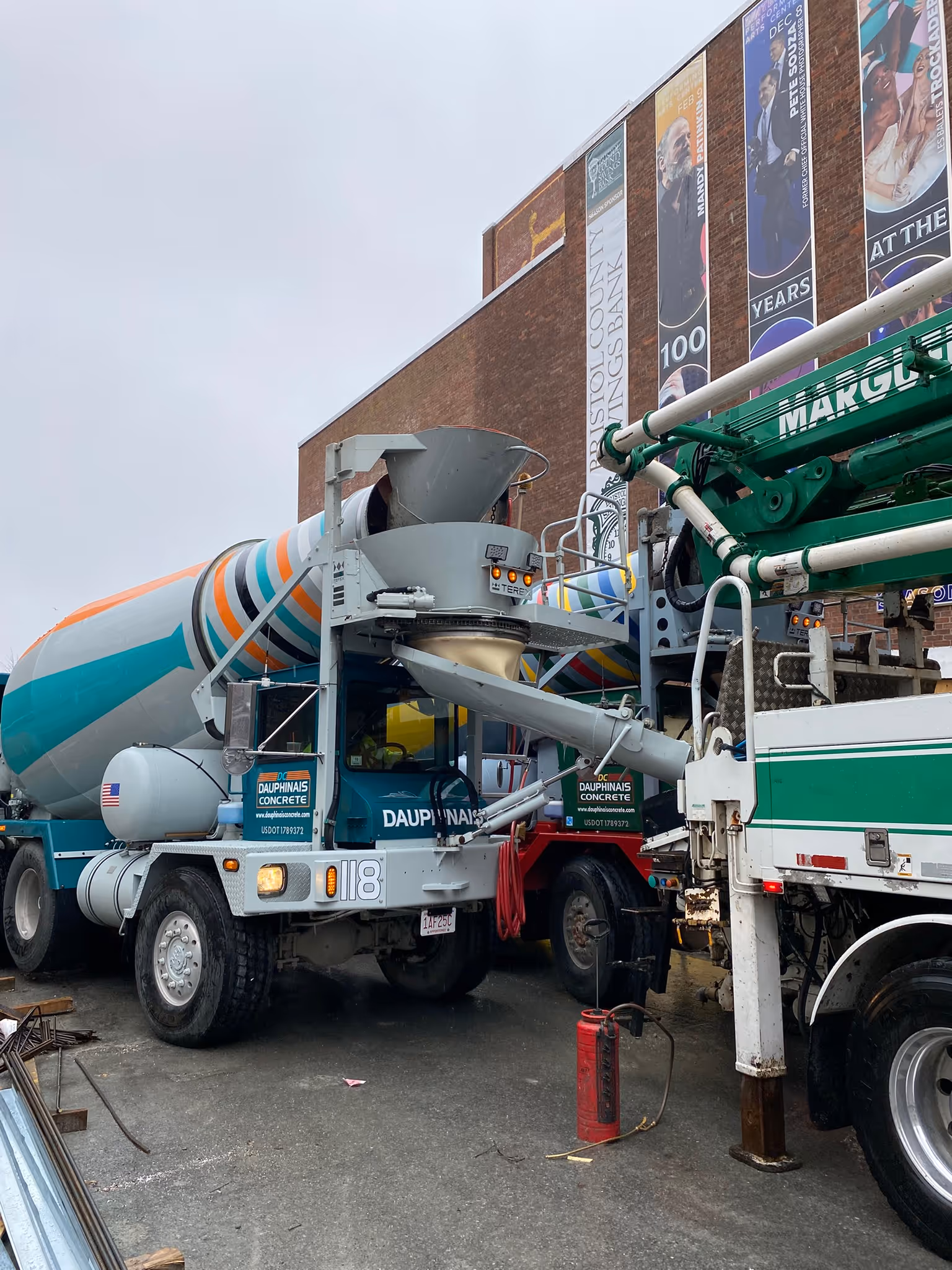 The front of a mixer truck, in the process of pouring concrete. 