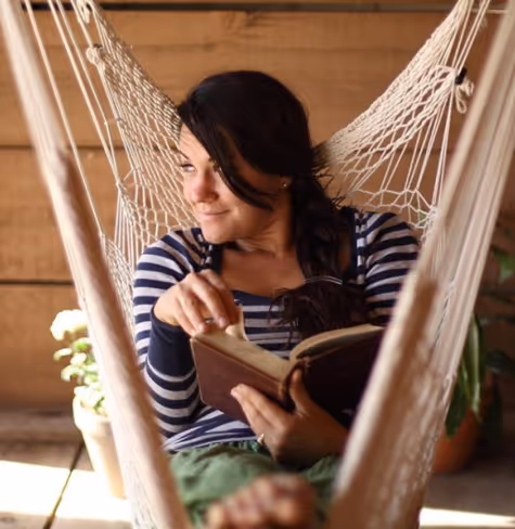 Sara laying back and reading a book in her white hammock chair