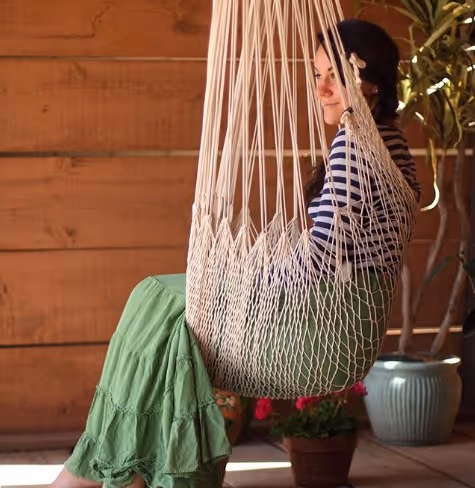 Sara sitting upright in a white hammock chair