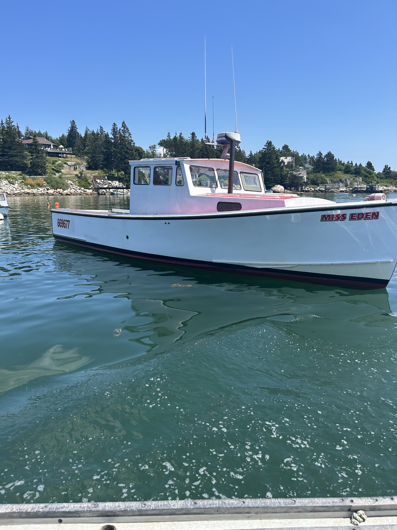 Miss Eden lobster boat moored in a Maine harbor cove on a clear summer day