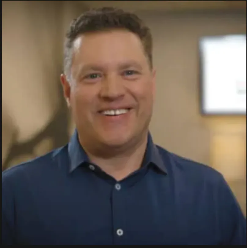 Man in a dark suit and striped tie with a blurred-out face area.