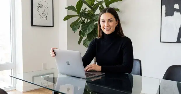 Hyperrealistic AI Avatar presenter working on a laptop in a modern home office environment.