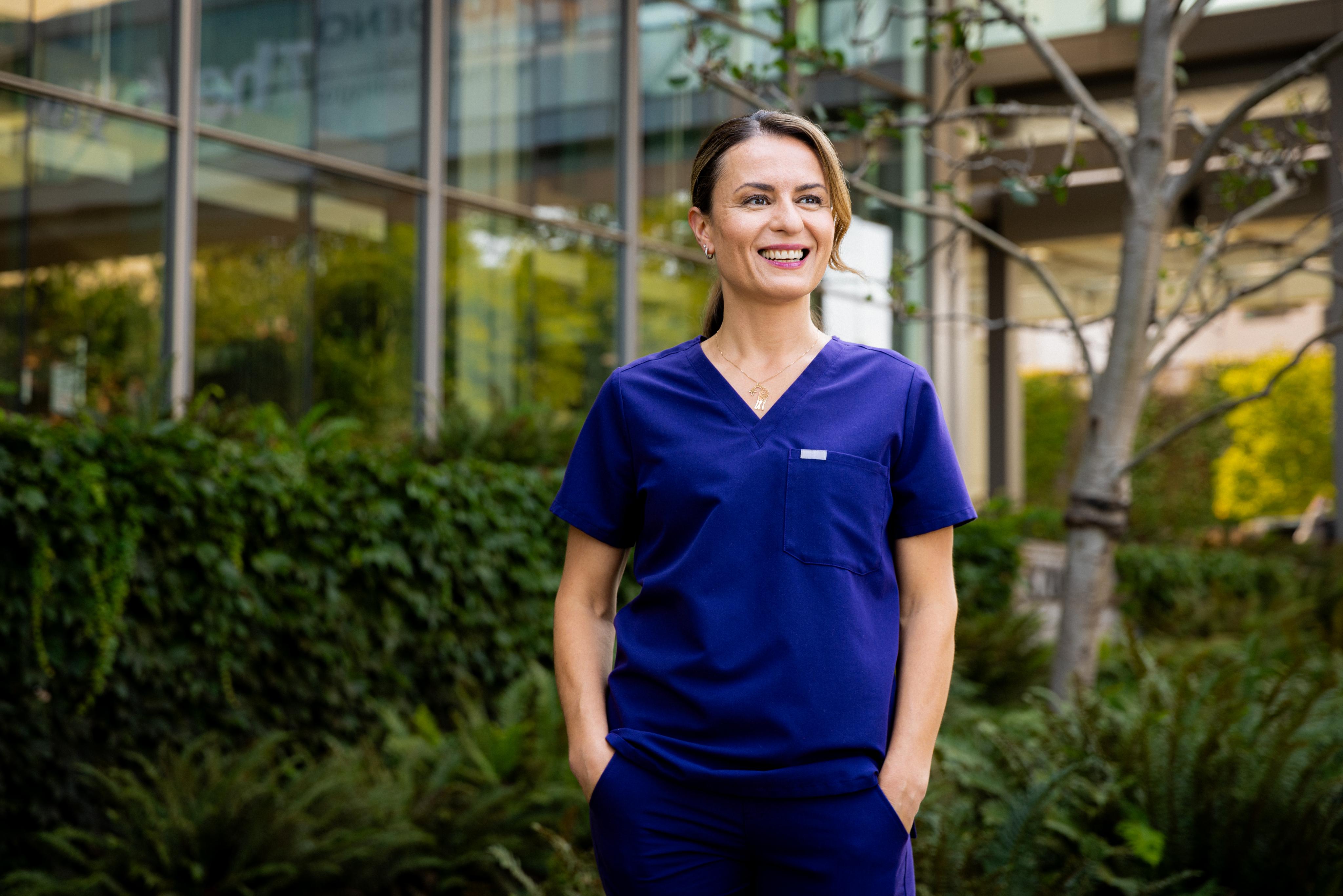 Woman in scrubs in front of a hospital