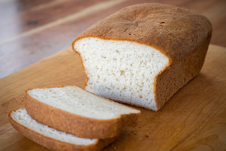 Sliced gluten-free french bread loaf on cutting board