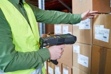 Man using a Warehouse Management System device to scan a box