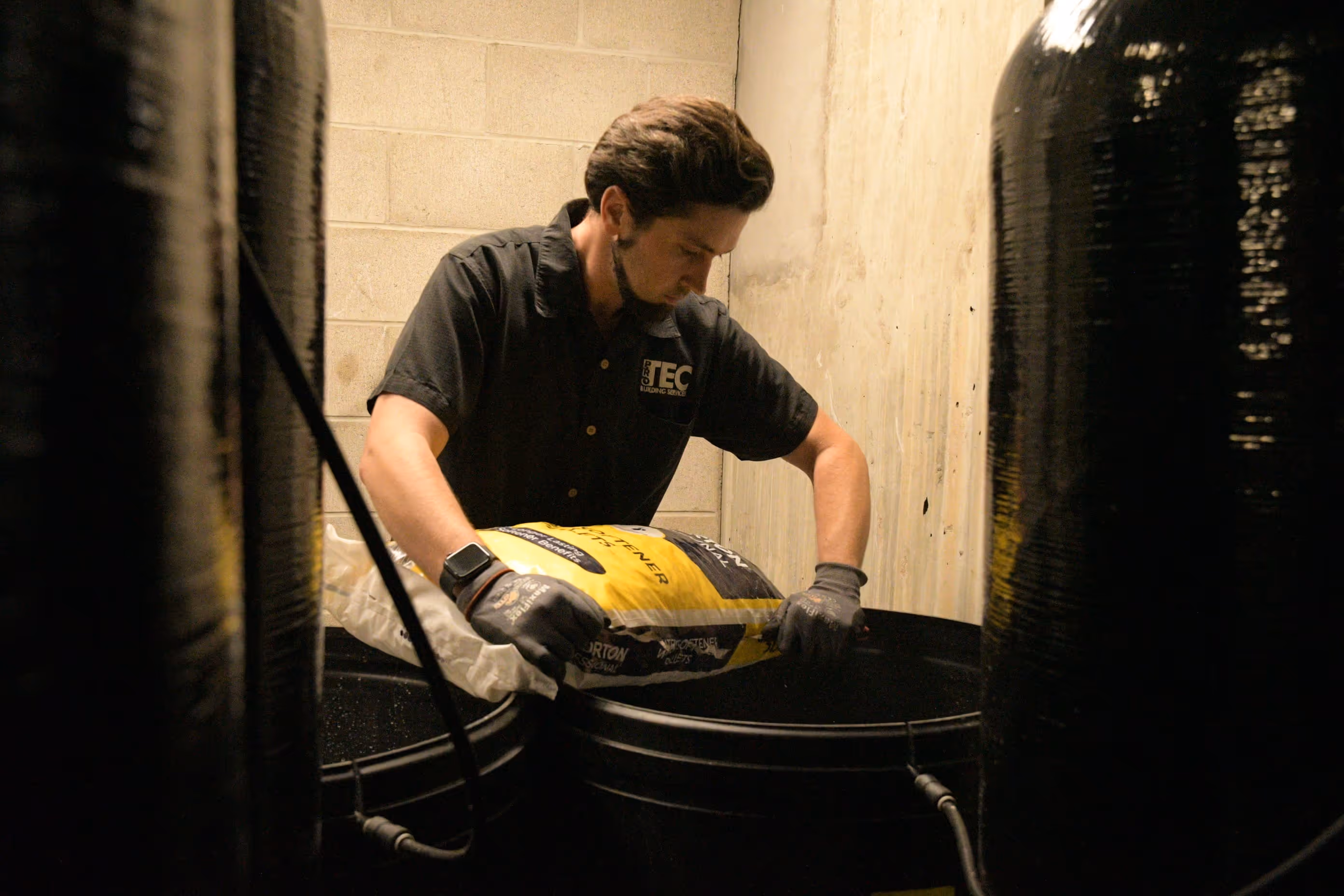 A man in a black shirt is working on a tank.